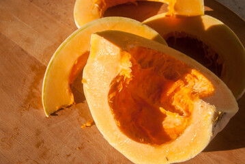 Cut raw pumpkin closeup on wooden table as autumn food background