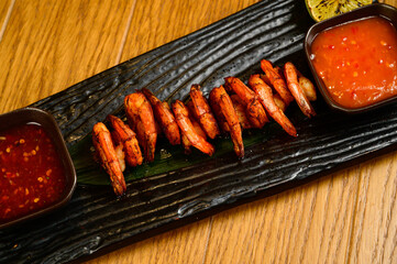 Delicious roasted shrimps on skewers with sauce and lemon