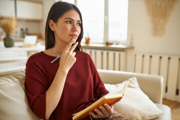 Thoughtful pensive young woman holding hand on her chin, having deep in thoughts look, thinking...