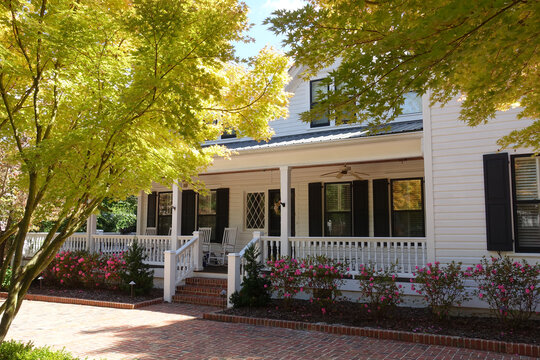 Charming White House with Brick Driveway and Front Porch in Autumn