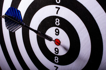 Blue dart spiked in the center of black and white target. Selective focus.