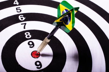 Dart with Brazil flag spiked in the center of black and white target. Selective focus.