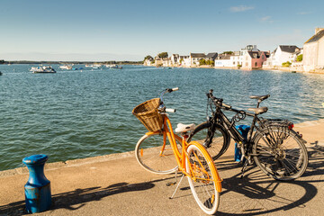 Bicyclettes et vélos orange et noir sur le quai d'un port breton à marée haute en fin...
