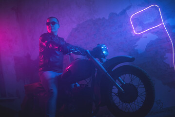 Naklejka na ściany i meble Motor biker in the neon lights on the old brick wall background.