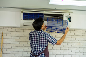 Asian technical engineer maintenance changing filter from air conditioner in the office 