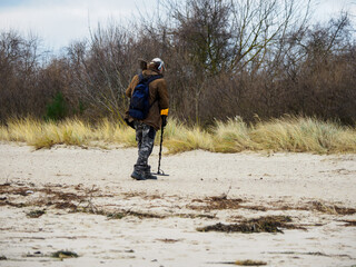 man searches the beach with a metal detector