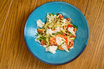 Vegetable vegetarian salad with tomatoes, peppers and onions on wooden table.