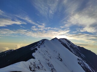 Sunset and clouds behind the snowy mountains of Caucasus