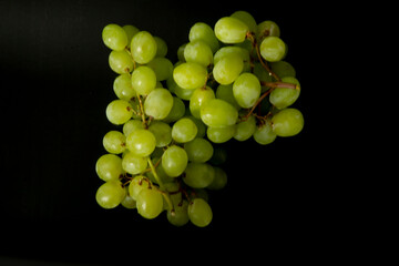 Branch of ripe green grapes isolated on a black background. Selective focus on the green grape