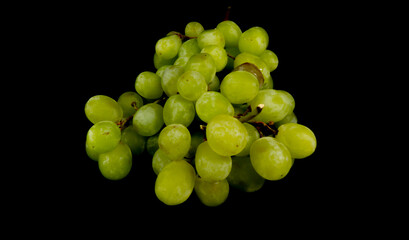 Branch of ripe green grapes isolated on a black background. Selective focus on the green grape