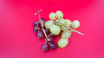 Fresh red and green grapes isolated on pink background. Selective focus on the fresh red and green grapes