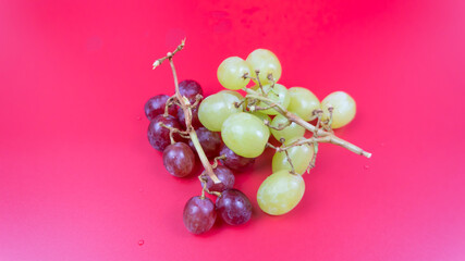 Fresh red and green grapes isolated on pink background. Selective focus on the fresh red and green grapes