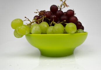 Fresh red and green grapes in a bowl isolated on pink background. Selective focus on the fresh red and green grapes.