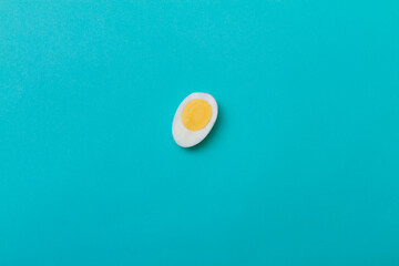 Half a peeled chicken egg with egg yolk and white on a blue background.