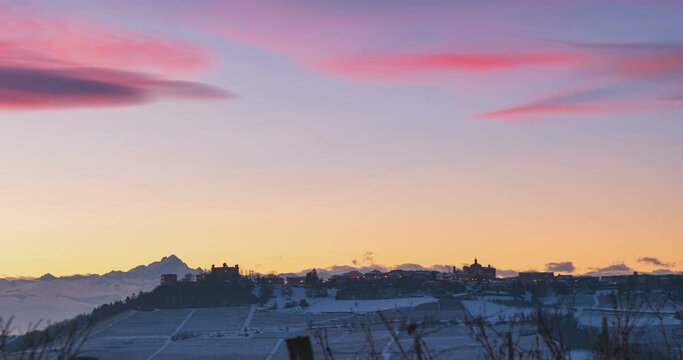 Time lapse sunset to night: famous Barolo wineyards, Novello medieval village perched on hill top, illuminated castle and baroque church, the Alps on the background at dusk