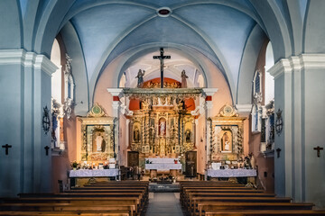 Inside a small christian church with wooden cross, golden altar and statues of saints