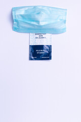 Disposable medical mask and disposable antiseptic gel containing 70 percent alcohol. White background and empty bottom space.