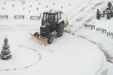 tractor-excavator removes snow in the city yard. work of public utilities