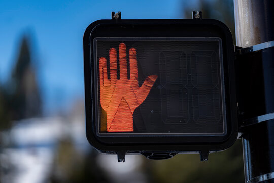 A red hand sign tells pedestrians not to cross a busy street.