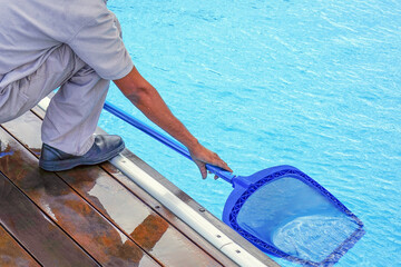 A pool cleaner holds a robot cleaner. Pool cleaner during his work. African hotel staff worker cleaning the pool