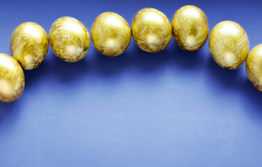 Top view easter composition. Easter greeting card with golden eggs on a blue background, copy space.