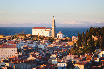 Fototapeta na wymiar Red roofs of the historical center of old town Piran with main church against the sunset sky and Adriatic sea. Aerial view, Slovenia