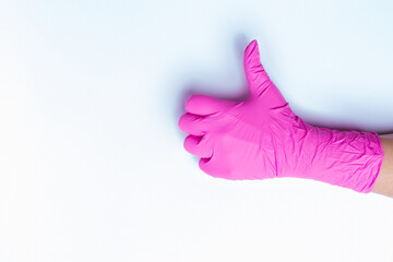 Hand in pink medical glove shows class isolated on white background with blank side space. Thumb up.