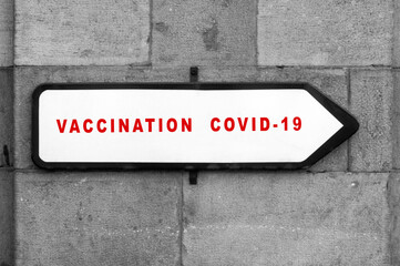 Closeup of covid-19 vaccination signboard on a stoned wall in outdoor