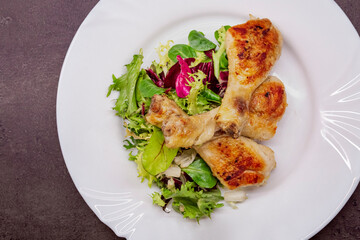 Chicken drumsticks with vegetable salad, grilled chicken legs on white plate, top view