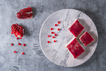 Flat lay view of pomegranate dessert over grey stone backdrop
