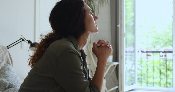 Side view confused unhappy anxious millennial woman feeling nervous waiting for important news, suffering from negative thoughts or indecision, having psychological problems sitting alone on sofa.