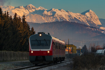 Old diesel train or multiple unit driving towards the city with majestic morning mountains in the...