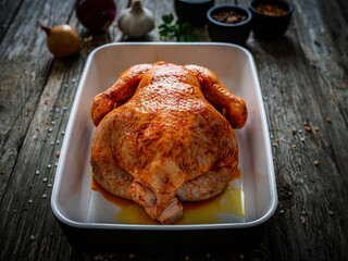 Fresh raw chicken on wooden table prepared to roast
