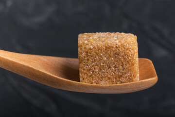 Cube of brown cane sugar in a wooden spoon of macro