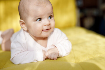 Adorable smiling baby in sunny bedroom. Newborn baby is resting in bed. Family morning at home.