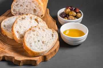 Traditional Italian ciabatta with olives and olive oil on a wooden board on the table. Craft bread and healthy food concept