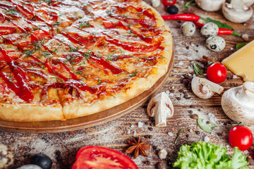 The pizza is surrounded by raw ingredients on the boards