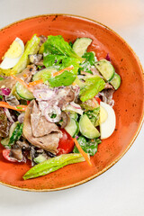 Vegetable vegetarian salad with tomatoes, peppers and onions on white table.