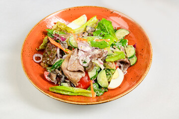 Vegetable vegetarian salad with tomatoes, peppers and onions on white table.