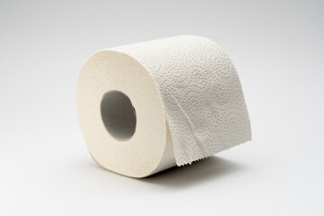 White toilet paper roll on a neutral white background. Full bathroom tissue out of recycled material.