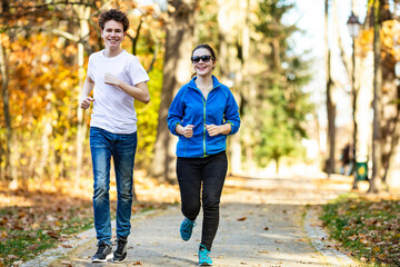 Obraz premium Teenage girl and boy running in city park 