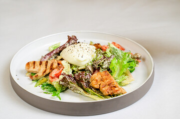 Caesar salad with croutons, quail eggs, cherry tomatoes and grilled chicken in white table
