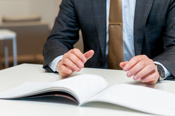 パンフレットを手に相手（お客様）に説明（営業）をするビジネスマン（セールスマン）