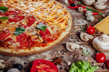 The pizza is surrounded by raw ingredients on the boards