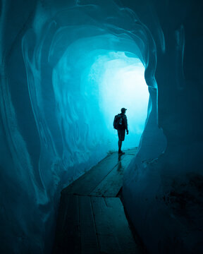 Vertical shot of a person with a backpack walking in the Rhone Glacier in Switzerland