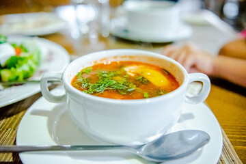 Kharcho soup is a traditional national dish of Asian cuisine. Side view of a dining table in a restaurant. A plate of soup in a white bowl