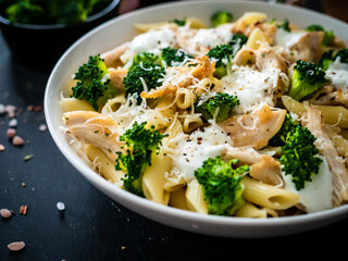 Penne with roast chicken meat, broccoli, parmesan and cream sauce  on black wooden table