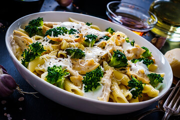 Penne with roast chicken meat, broccoli, parmesan and cream sauce  on black wooden table