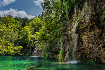 Waterfalls coming down from tall cliffs or rocks to turquoise coloured lake in Plitvice Lakes National Park UNESCO World Heritage, Croatia