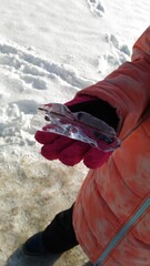 The child holds ice in the palm of his hand